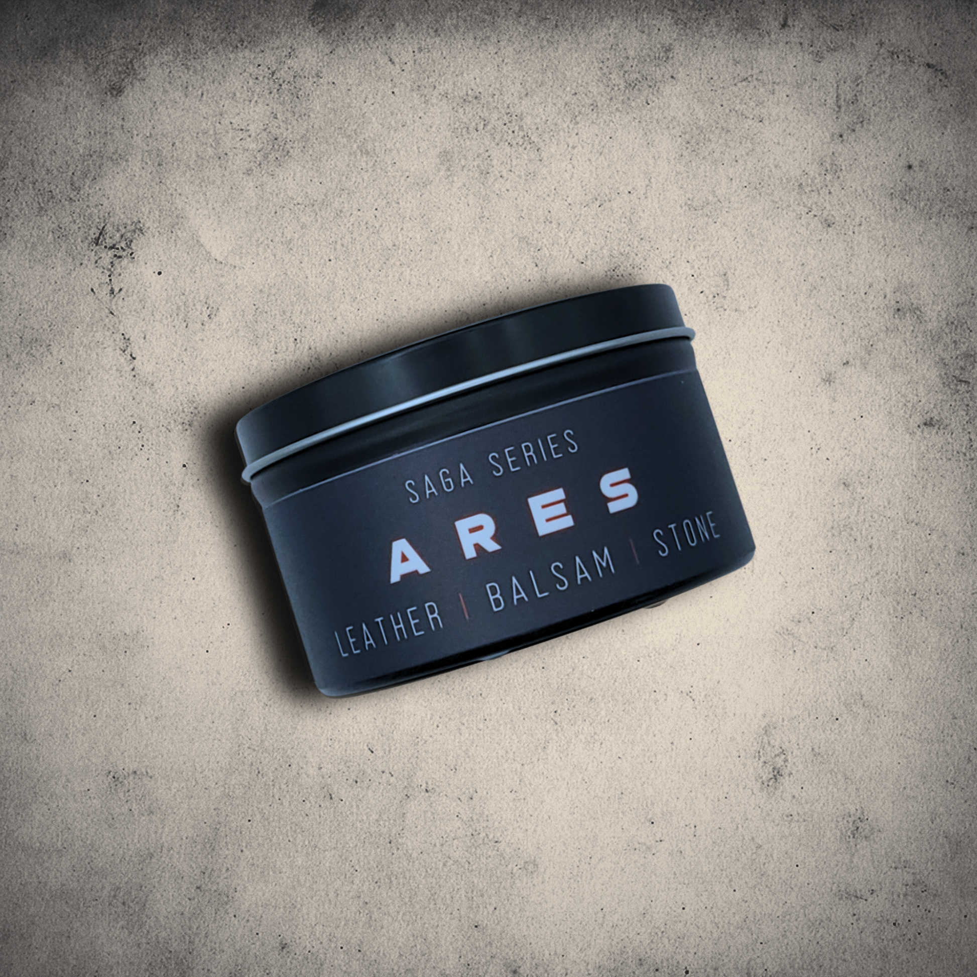 Emberlight Archives Ares candle in an 8oz black tin with black label against a gray stone background, Leather & Balsam scent.