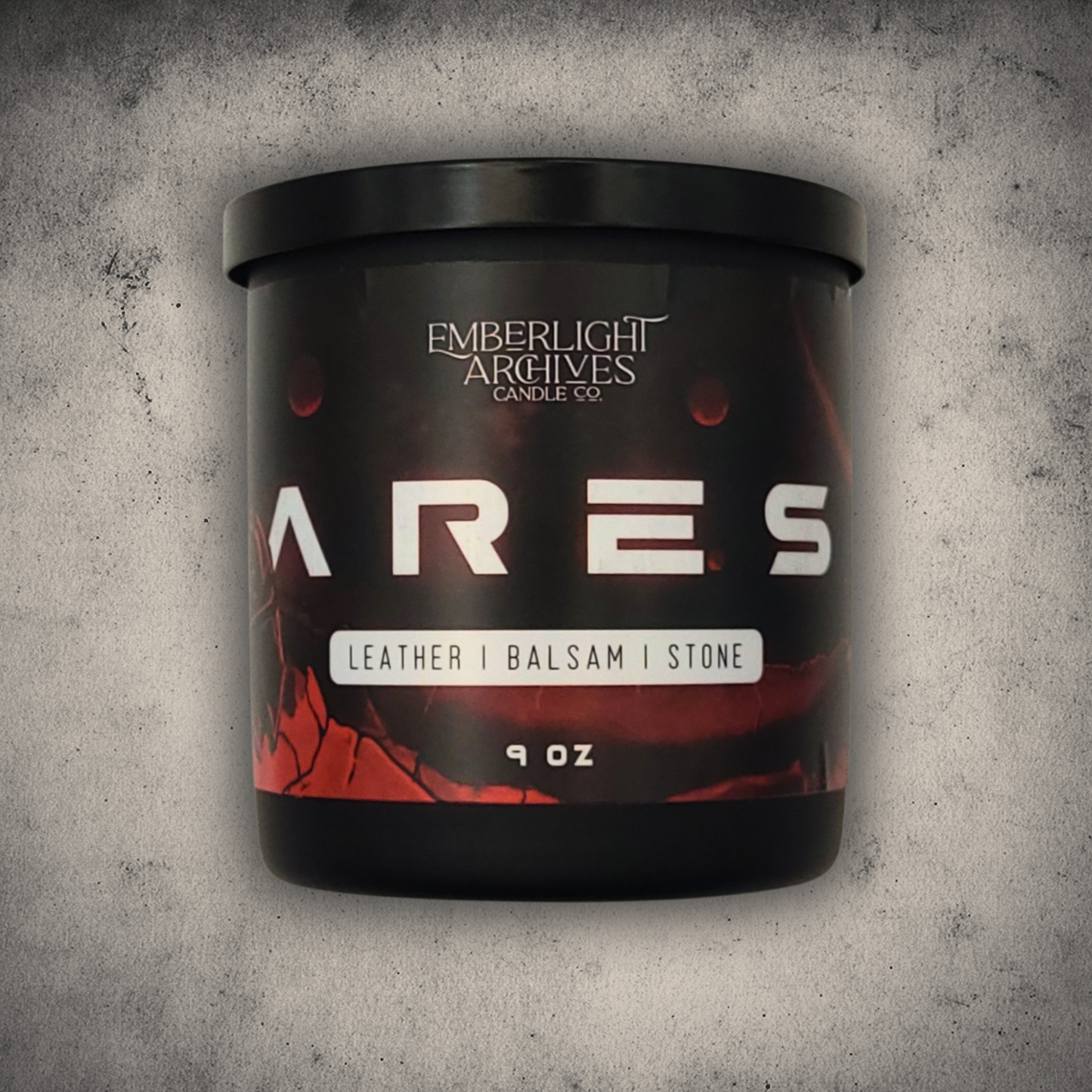 Emberlight Archives Ares candle in a 9oz black glass jar with illustrated red planet label against a gray stone background, Leather & Balsam scent.