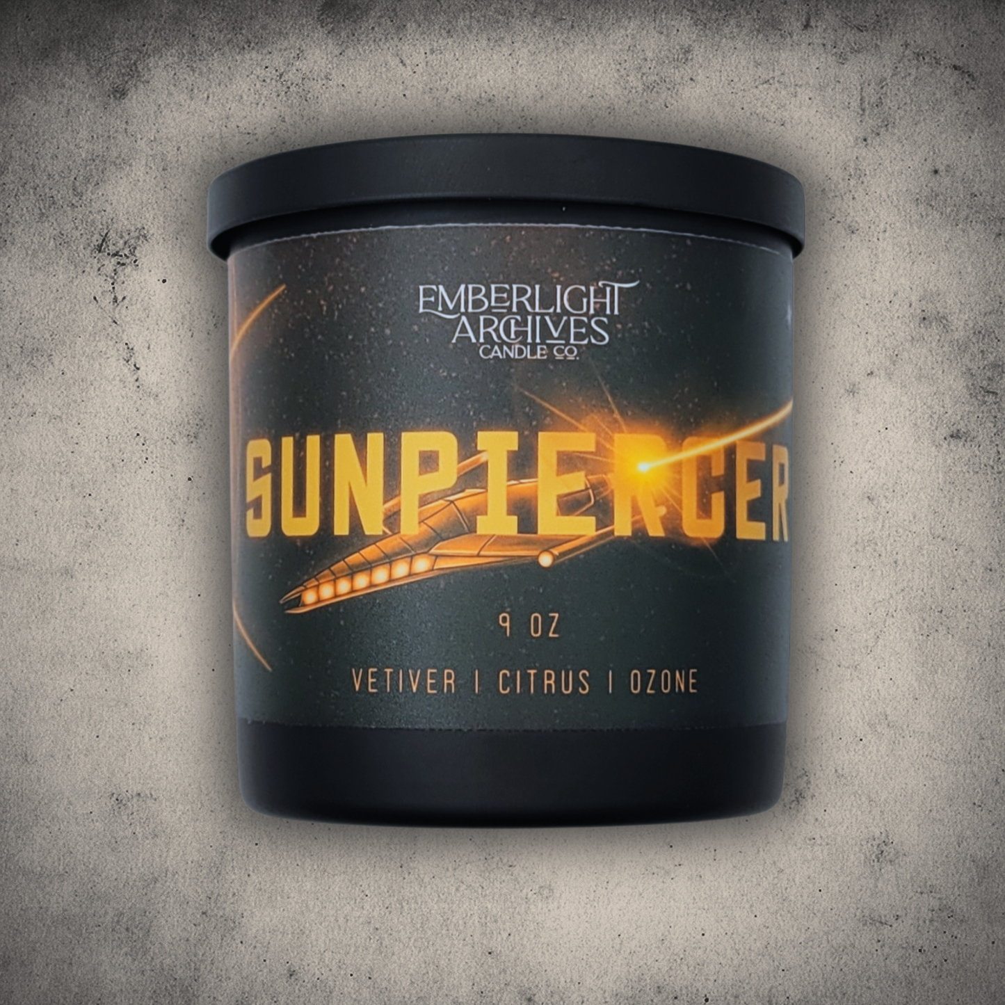 Emberlight Archives Sunpiercer candle in a 9oz black glass jar with illustrated spaceship label against a gray stone background, Citrus scent.