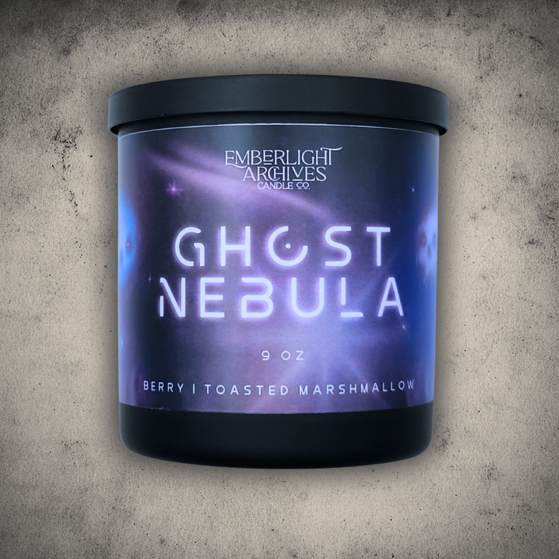 Emberlight Archives Ghost Nebula candle in a 9oz black glass jar with illustrated nebula label against a gray stone background, Berry & Marshmallow scent.