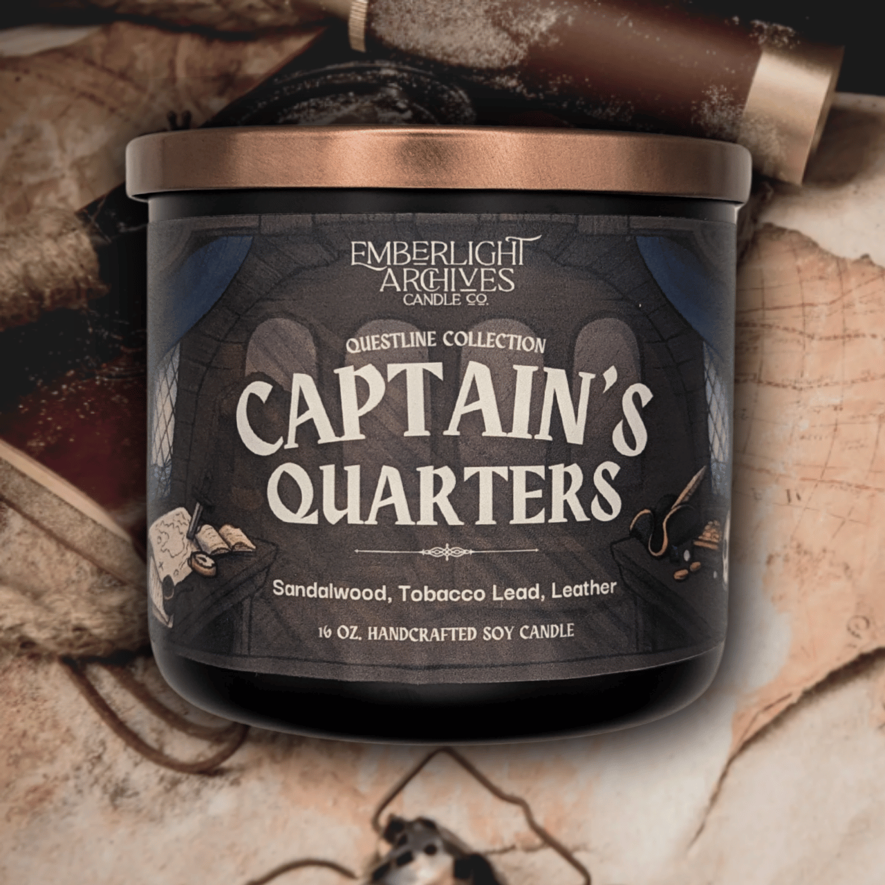 16oz Captain's Quarters candle by Emberlight Archives in a black glass jar with illustrated pirate ship label against a vintage table with maps background, Tobacco and Sandalwood scent.