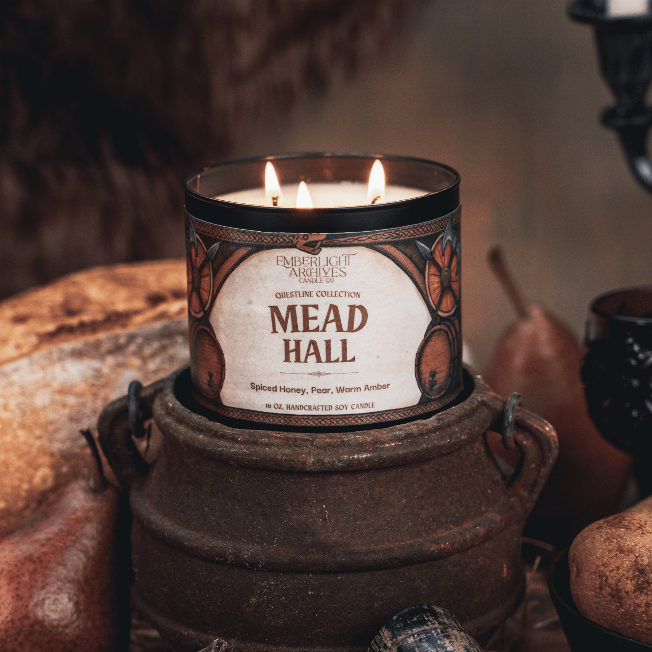 16oz Emberlight Archives Mead Hall candle in a rustic setting with warm lighting.