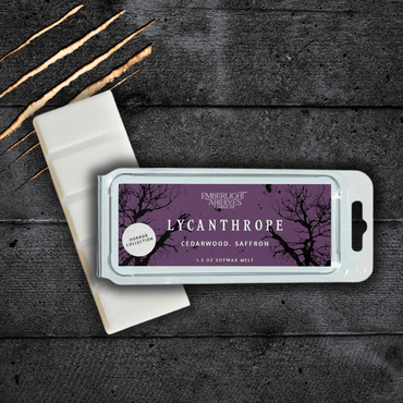 Lycanthrope wax melt bar by Emberlight Archives with a purple label against a dark wood background, Cedarwood and Saffron scent.