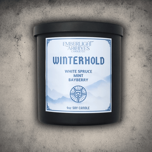 Emberlight Archives Winterhold candle in a 9oz black glass jar with white label against a gray stone background, Spruce, Mint, and Bayberry scent.