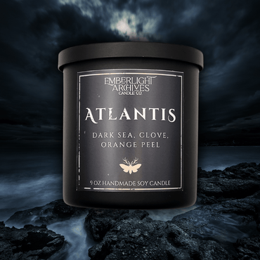 9oz Atlantis candle by Emberlight Archives in a black glass jar with dark label against a dark sea background, Dark Sea and Orange Peel scent.