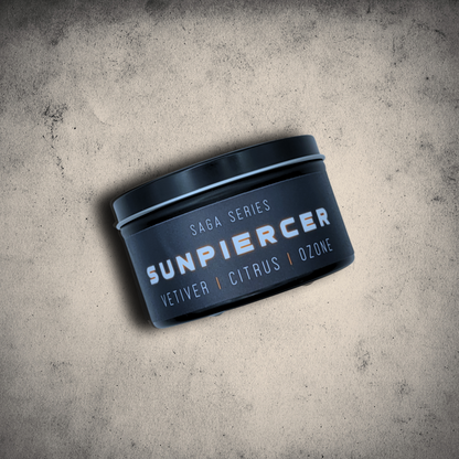 Emberlight Archives Sunpiercer candle in an 8oz black tin with black label against a gray stone background, Citrus scent.