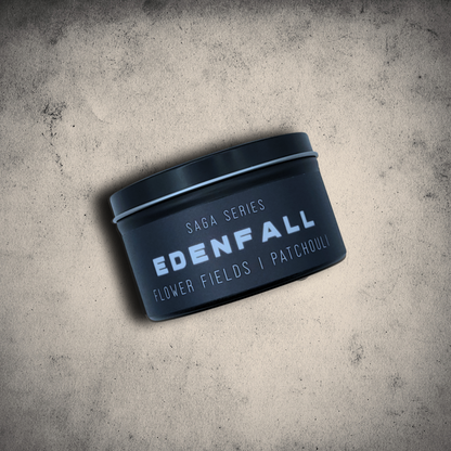 Emberlight Archives Edenfall candle in an 8oz black tin with illustrated sci-fi label against a gray stone background, Patchouli & Flower Fields scent.