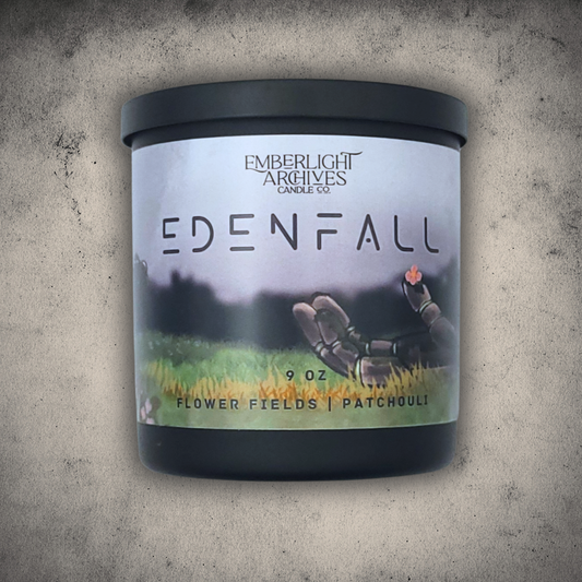 9oz Edenfall candle in a black jar with label featuring a hand holding a flower on a textured gray stone background, Flower Fields & Patchouli scent.