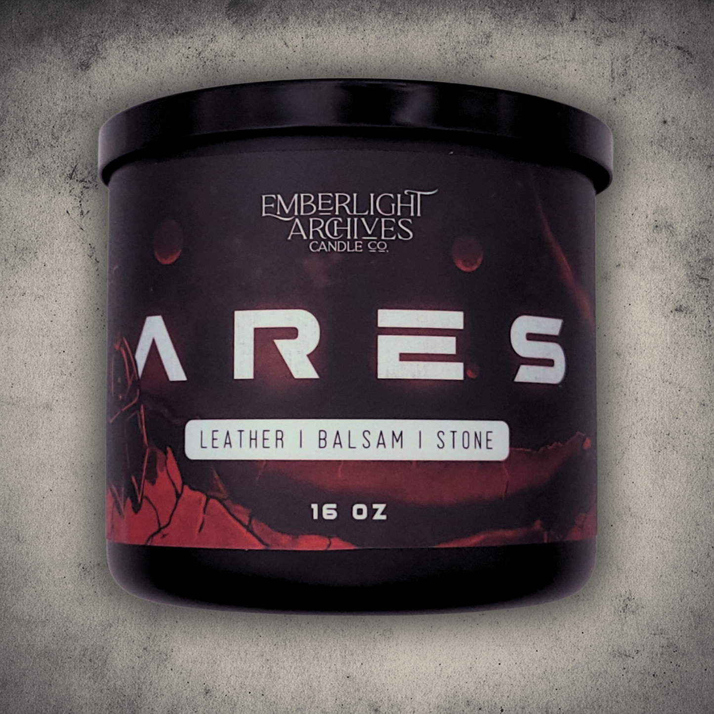 Emberlight Archives Ares candle in a 16oz black glass jar with illustrated red planet label against a gray stone background, Leather & Balsam scent.