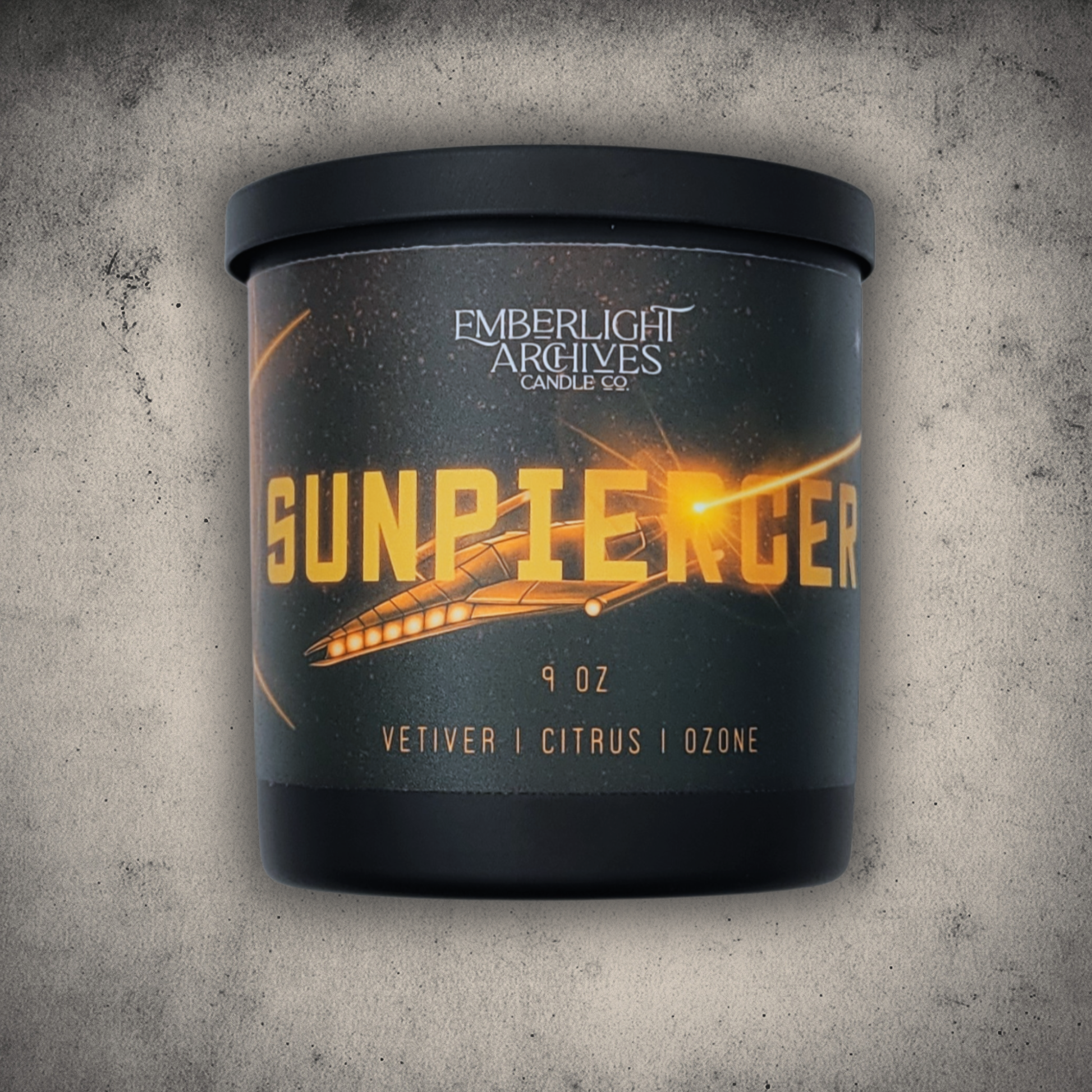 Emberlight Archives Sunpiercer candle in a 9oz black glass jar with illustrated spaceship label against a gray stone background, Citrus scent.