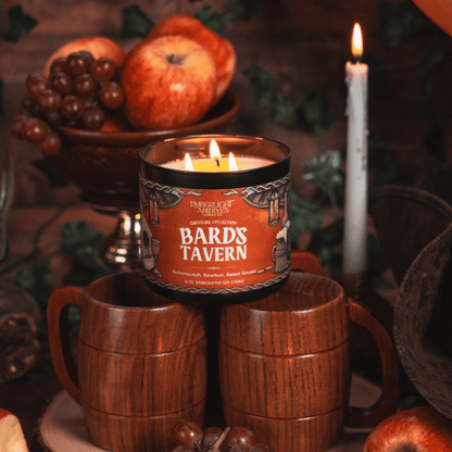 Candle labeled 'Bards Tavern' with wooden mugs and fruit in the background