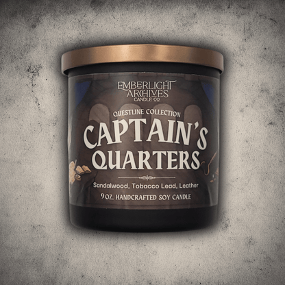 Emberlight Archives Captain's Quarters candle in a 9oz black glass jar with illustrated label against a gray stone background, Tobacco and Sandalwood scent.