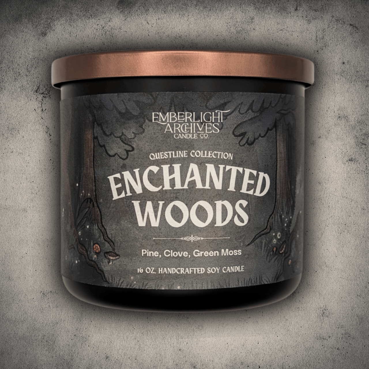Emberlight Archives Enchanted Woods candle in a 16oz black glass jar with illustrated forest label against a gray stone background, Pine and Clove scent.