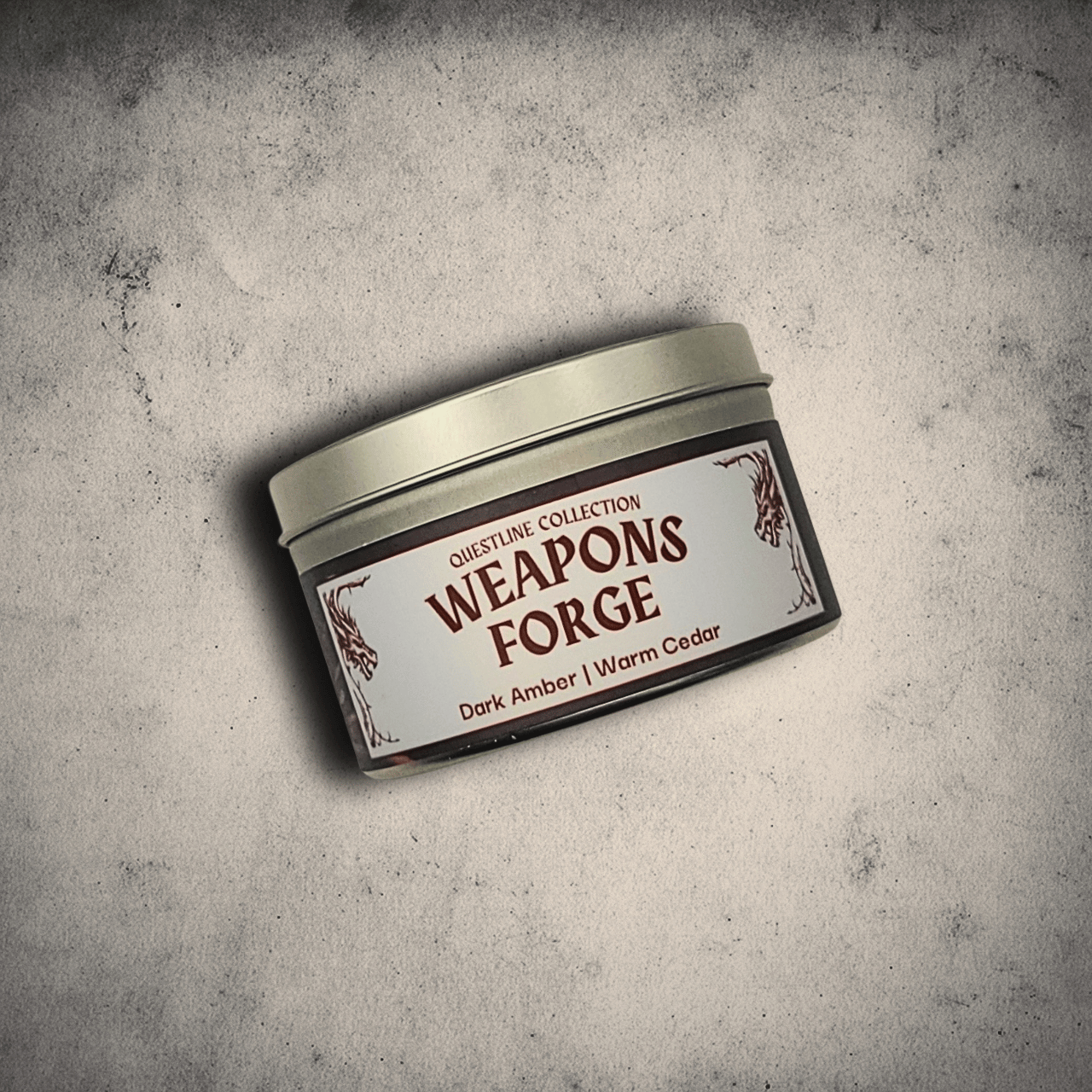 Emberlight Archives Weapon's Forge candle in an 8oz tin with illustrated blacksmith label against a gray stone background, Amber and Cedar scent.