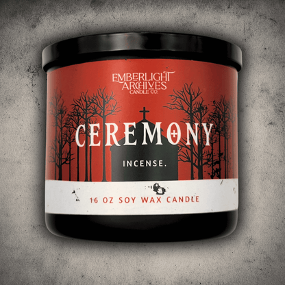 Emberlight Archives Ceremony candle in a 16oz black glass jar with red church scene label against a gray stone background, Incense scent.