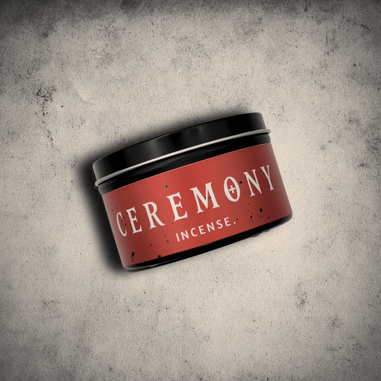 Emberlight Archives Ceremony candle in an 8oz black tin with red label against a gray stone background, Incense scent.