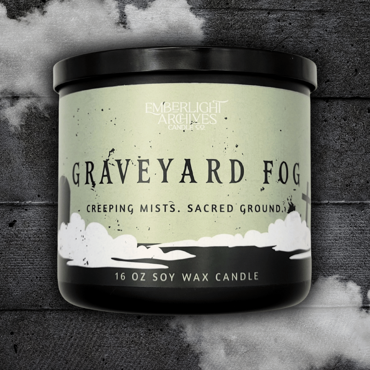 16oz Graveyard Fog candle by Emberlight Archives in a black jar with pale green label against a dark wood background.