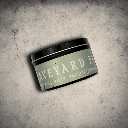 Graveyard Fog candle in an 8oz tin by Emberlight Archives on a textured gray background.