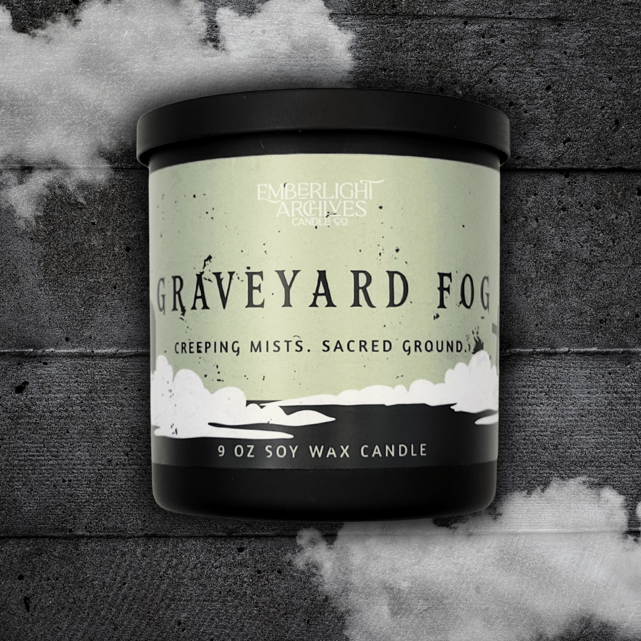 9oz candle in a black jar labeled 'Graveyard Fog' by Emberlight Archives on a textured dark background with smoke effect.