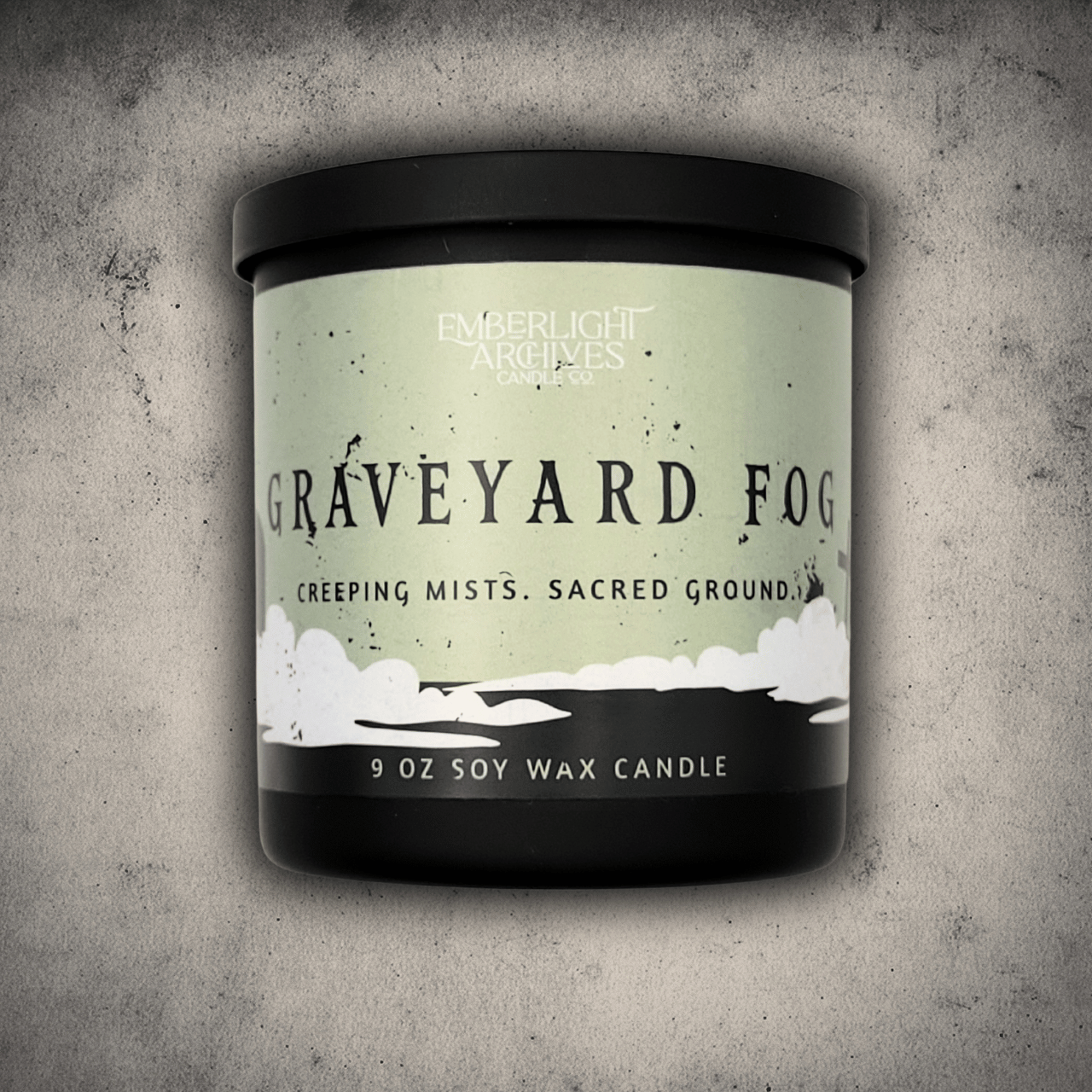 9oz candle in a black jar by Emberlight Archives with 'Graveyard Fog' label on a textured gray background