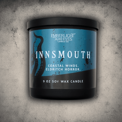 Emberlight Archives Innsmouth candle in a 9oz black glass jar with blue tentacles label against a gray stone background, Coastal Winds and Black Coral scent.