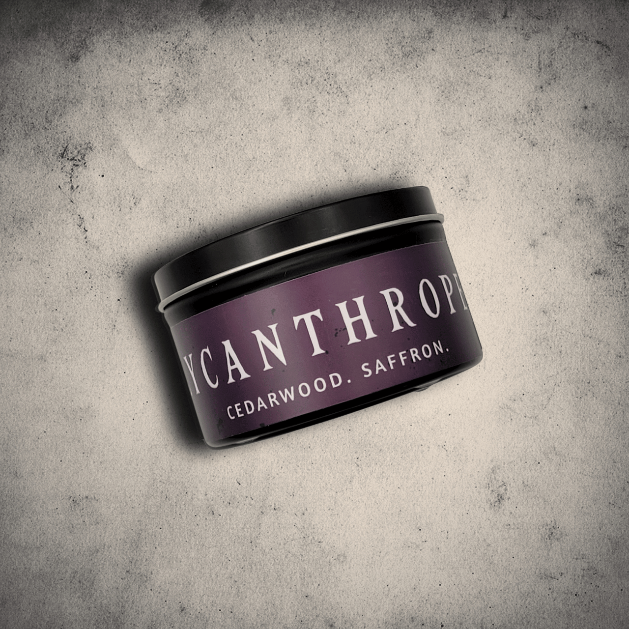 Emberlight Archives Lycanthrope horror candle – 8oz black tin with purple label against a gray stone background, Cedarwood & Saffron scent.