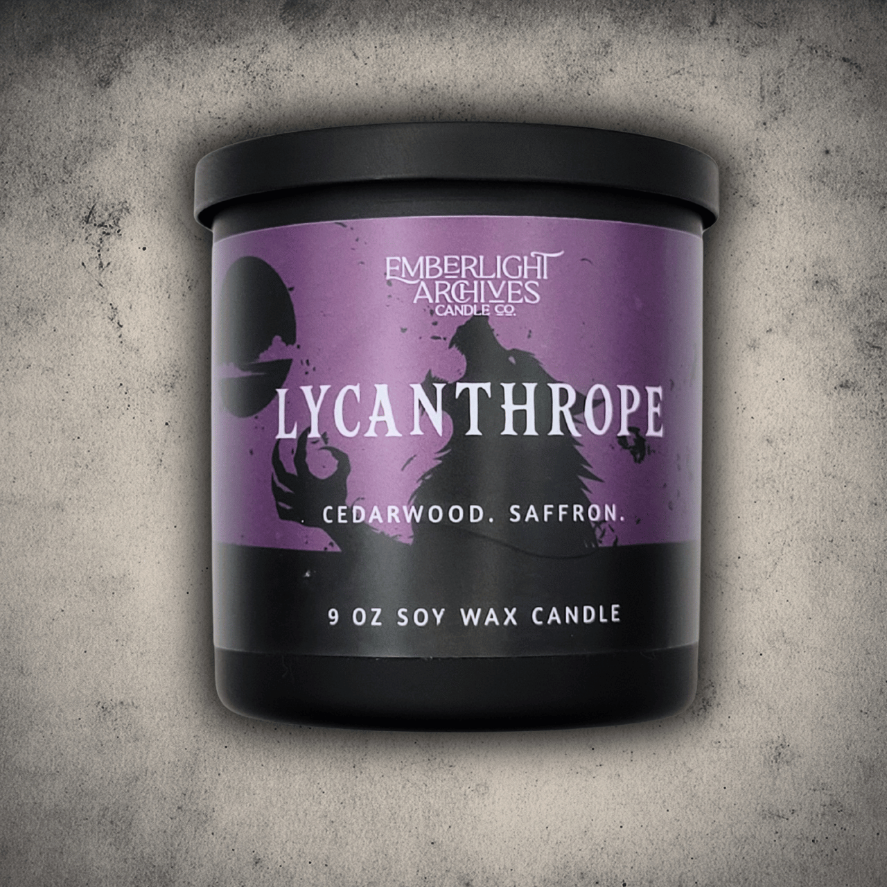 Emberlight Archives Lycanthrope horror candle – 9oz black glass jar with purple werewolf label against a gray stone background, Cedarwood & Saffron scent.