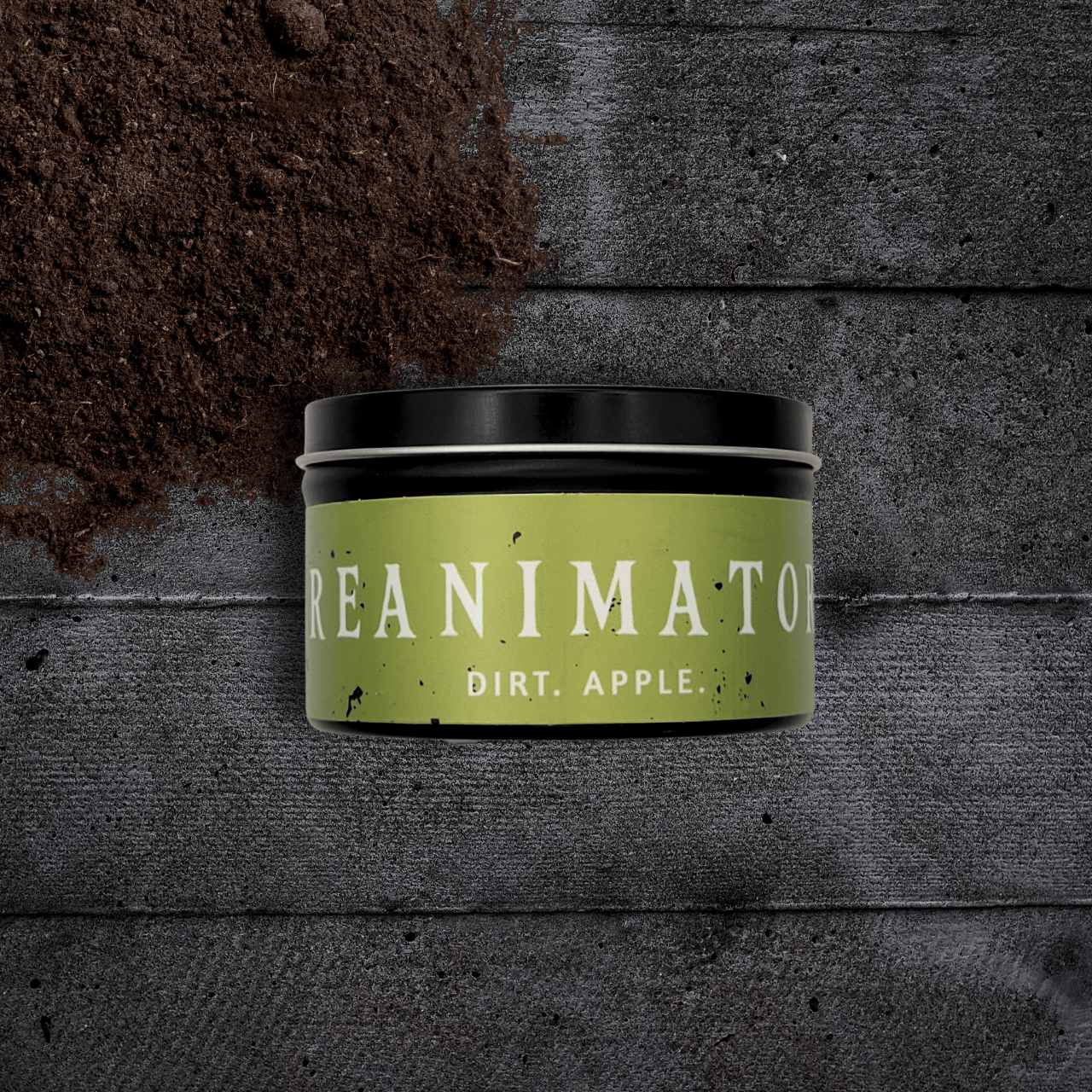 8oz Reanimator candle by Emberlight Archives in a black tin with bright green label against a dark wood background, Dirt and Apple scent.