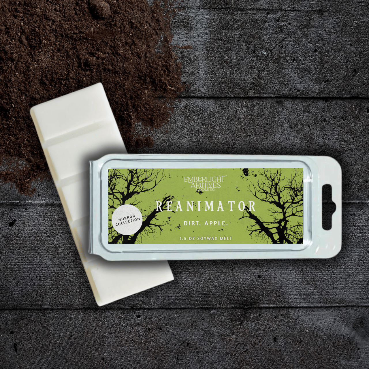 Reanimator wax melt bar by Emberlight Archives with a bright green label against a dark wood background, Dirt and Apple scent.