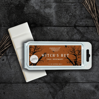 Witch's Hut wax melt bar by Emberlight Archives with an orange label against a dark wood background, Chai and Rosemary scent.