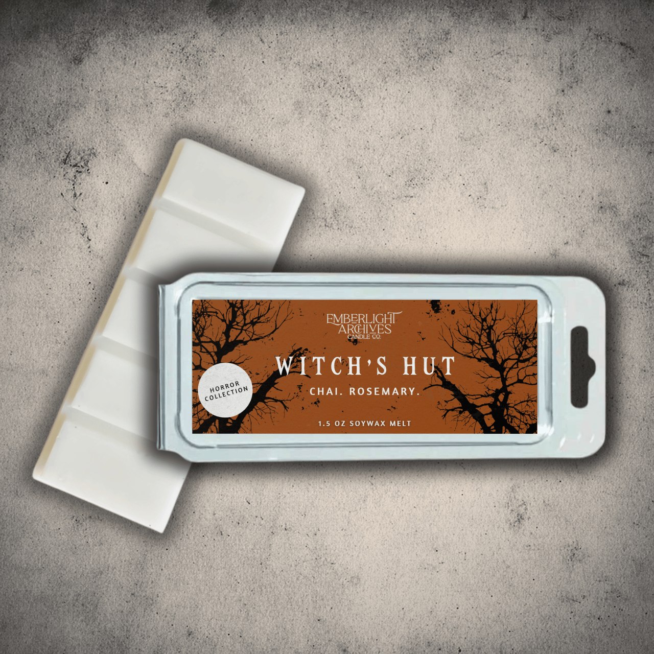 Emberlight Archives Witch's Hut wax melt bar with an orange label against a gray stone background, Chai and Rosemary scent.