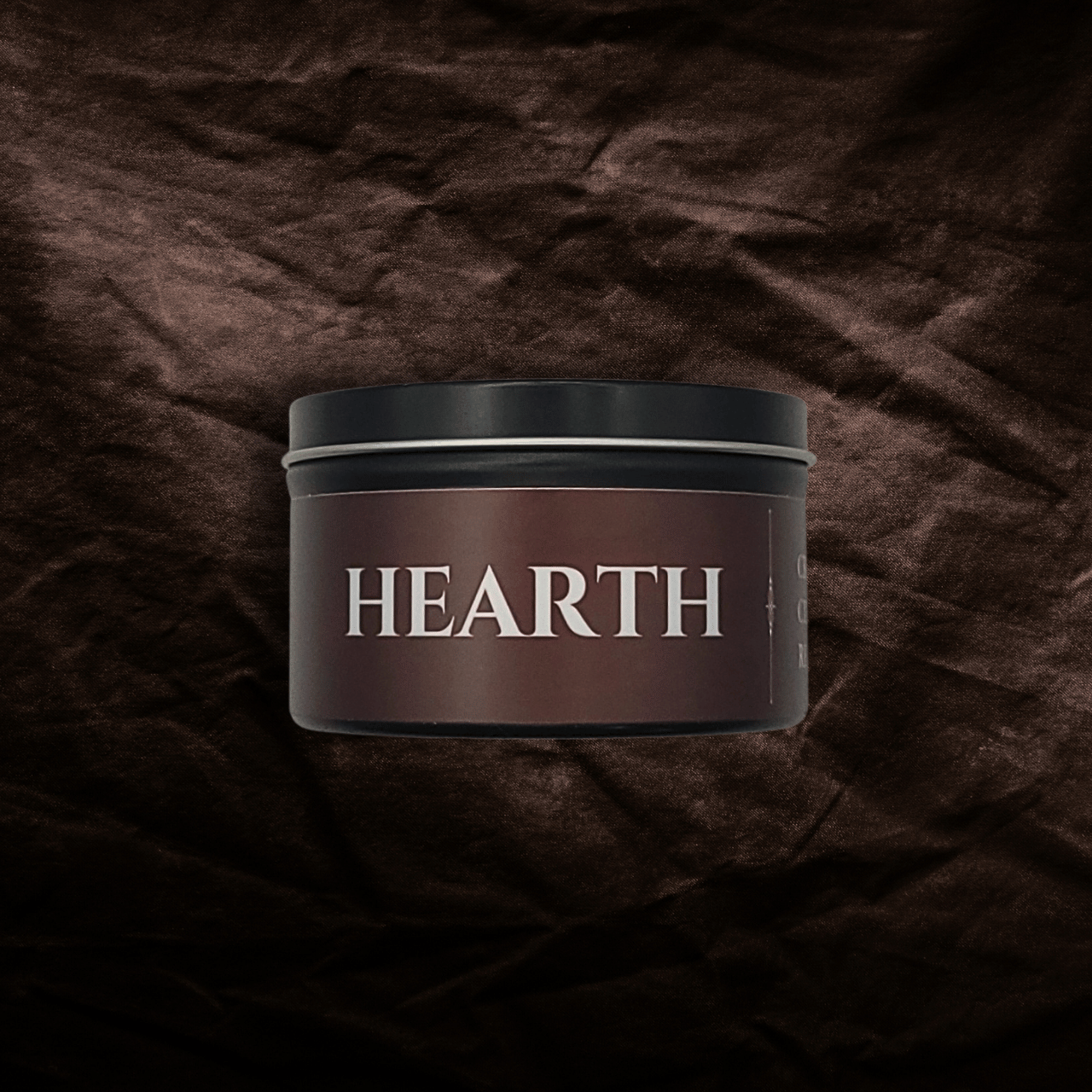 8oz Hearth candle by Emberlight Archives in a black tin with red label against a dark red background.