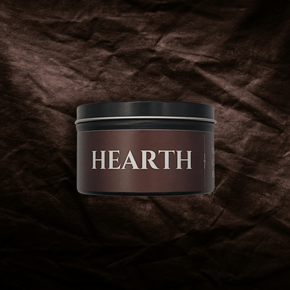 8oz Hearth candle by Emberlight Archives in a black tin with red label against a dark red background.