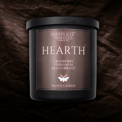 9oz Hearth candle by Emberlight Archives in a black glass jar with red label against a dark red background, Cranberry Cinnamon scent.