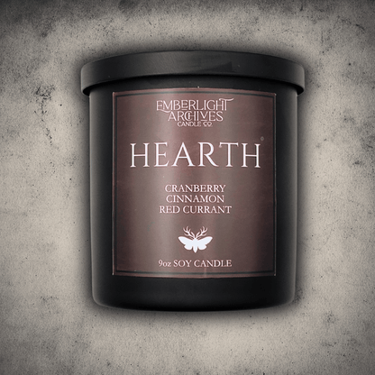 Emberlight Archives Hearth candle in a 9oz black glass jar with red label against a gray stone background, Cranberry Cinnamon scent.
