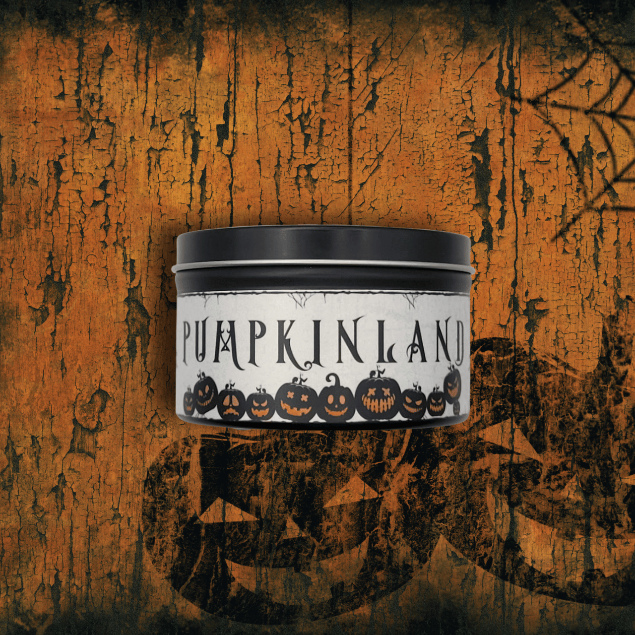 Candle in a tin labeled 'Pumpkinland' on a textured orange background with pumpkins.