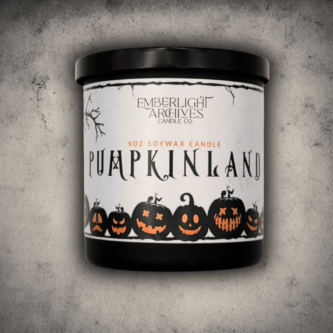 Emberlight Archives Pumpkinland candle in a 9oz black glass jar with pumpkin label against a gray stone background, Pumpkin Pie scent.