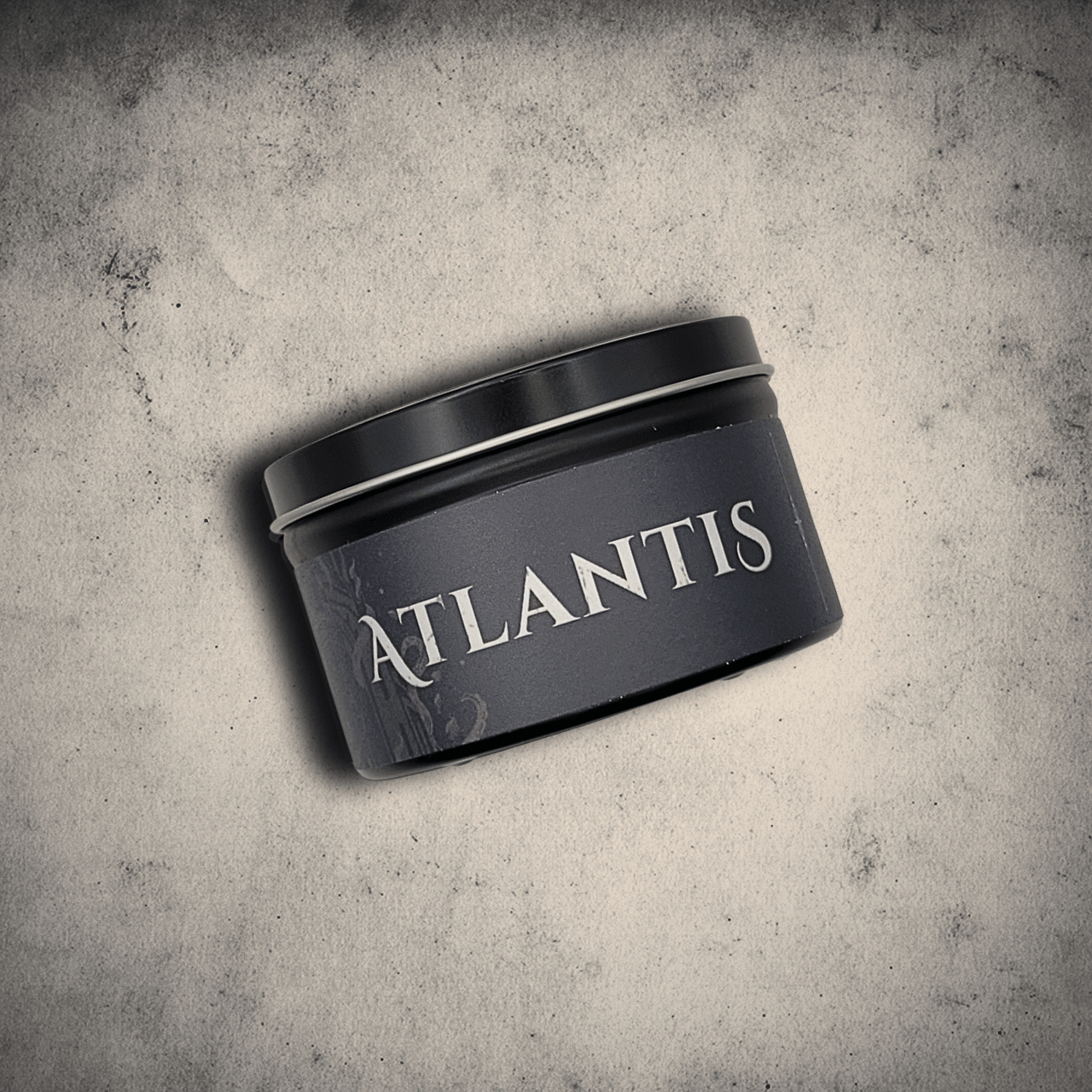 Emberlight Archives Atlantis candle in an 8oz black tin with dark label against a gray stone background, Dark Sea and Orange Peel scent.