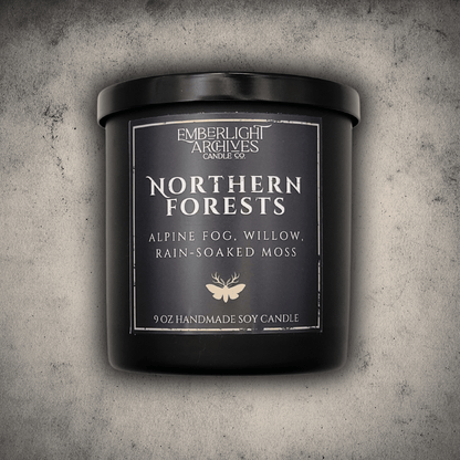 Emberlight Archives Northern Forests candle in a 9oz black glass jar with dark label against a gray stone background, Rain & Moss scent.