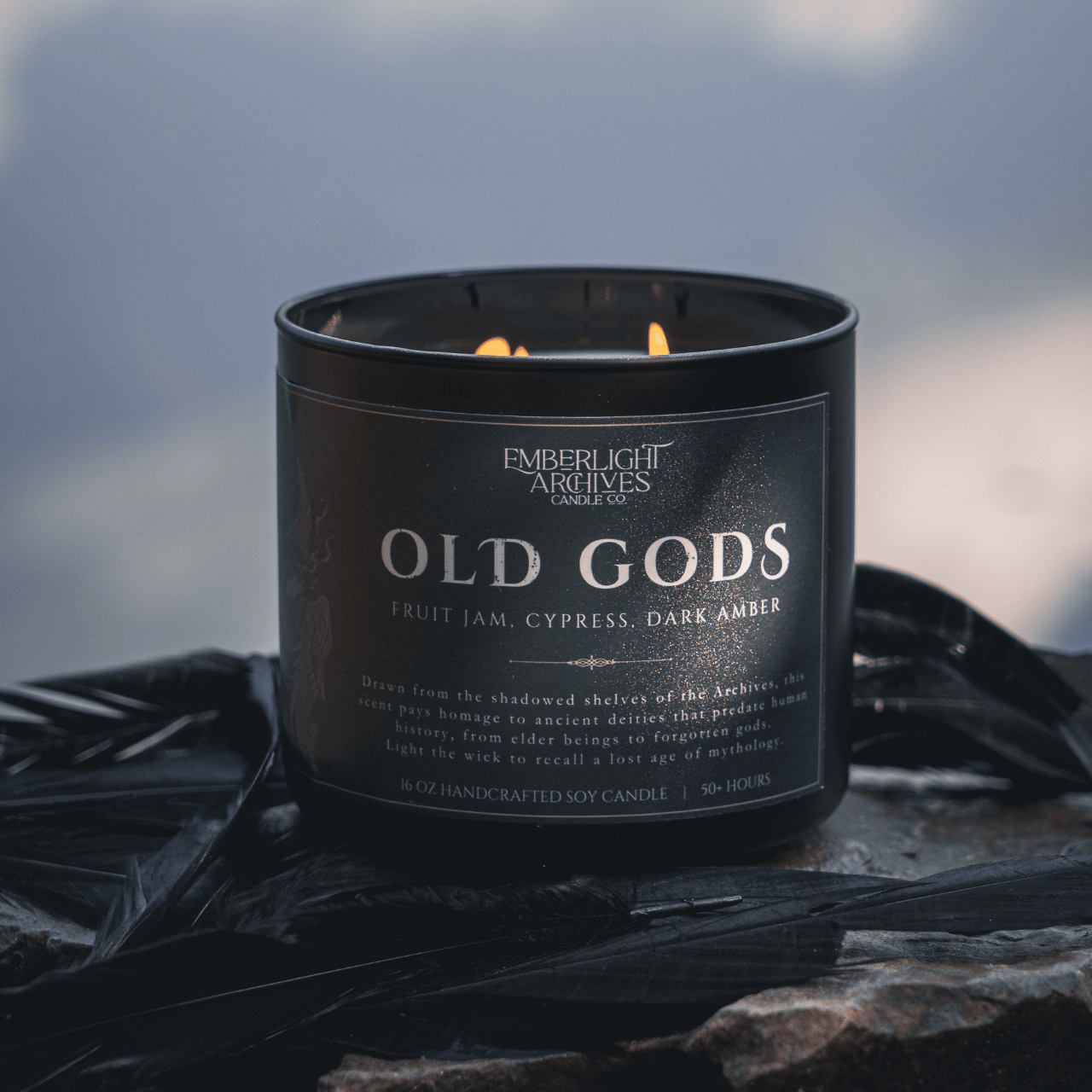 Black candle labeled 'Old Gods' by Emberlight Archives on a dark background