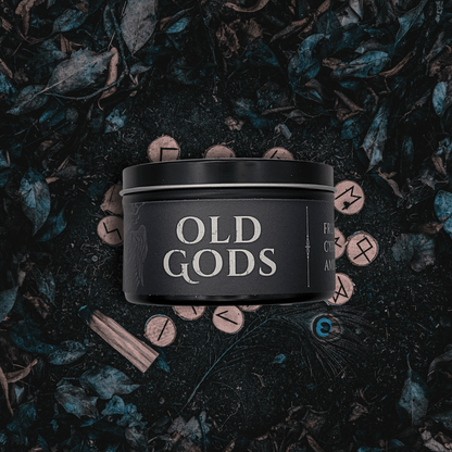 Black 8oz Old Gods candle by Emberlight Archives on a dark background with leaves and symbols.