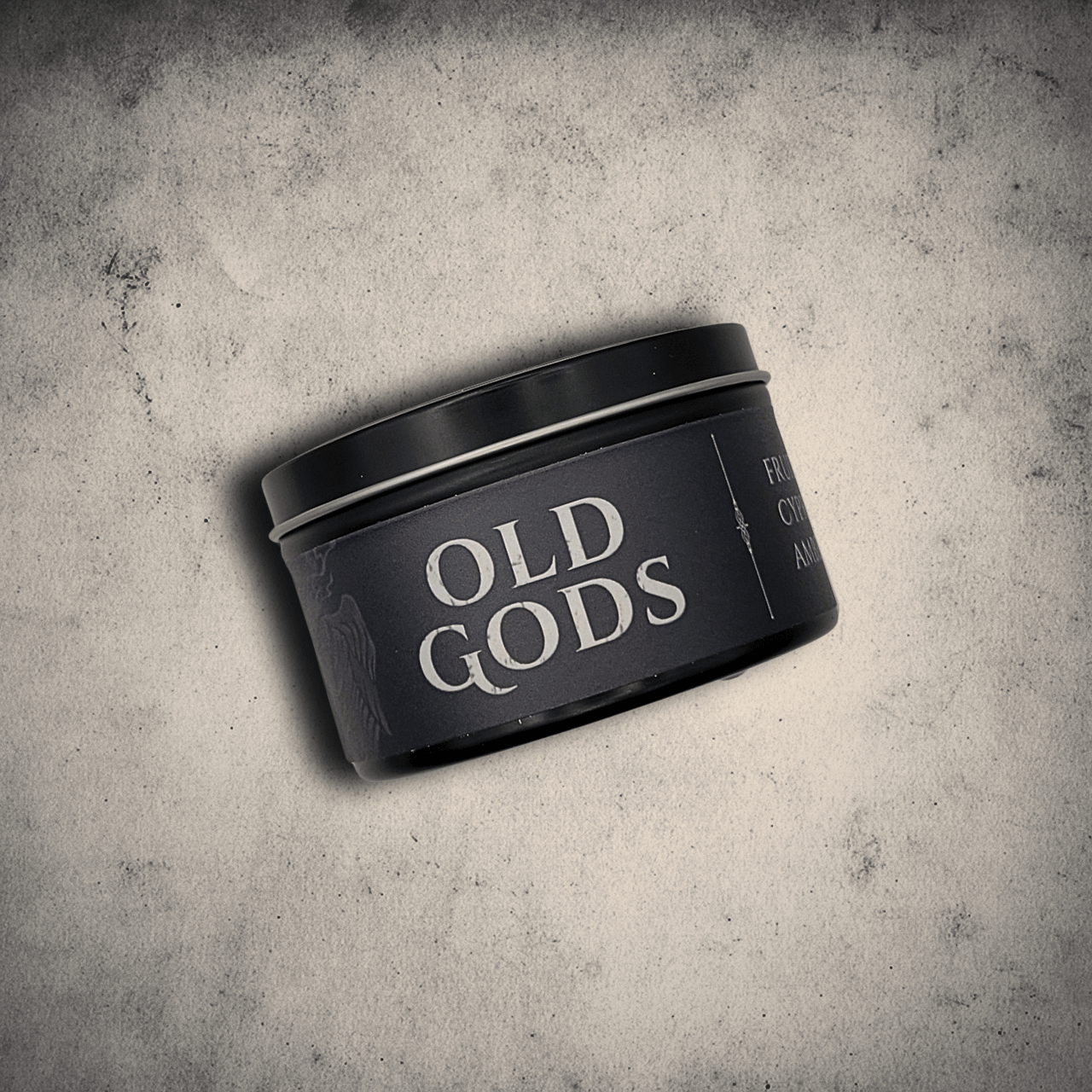 Emberlight Archives Old Gods candle in an 8oz black tin with dark label against a gray stone background, Fruit Jam & Musk scent.