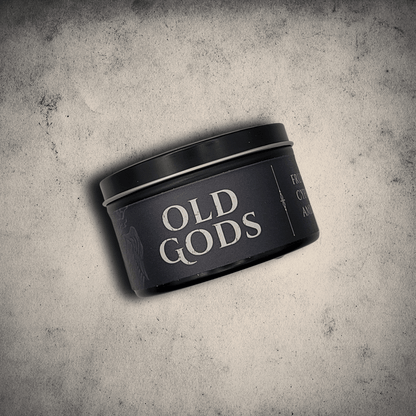 Emberlight Archives Old Gods candle in an 8oz black tin with dark label against a gray stone background, Fruit Jam & Musk scent.