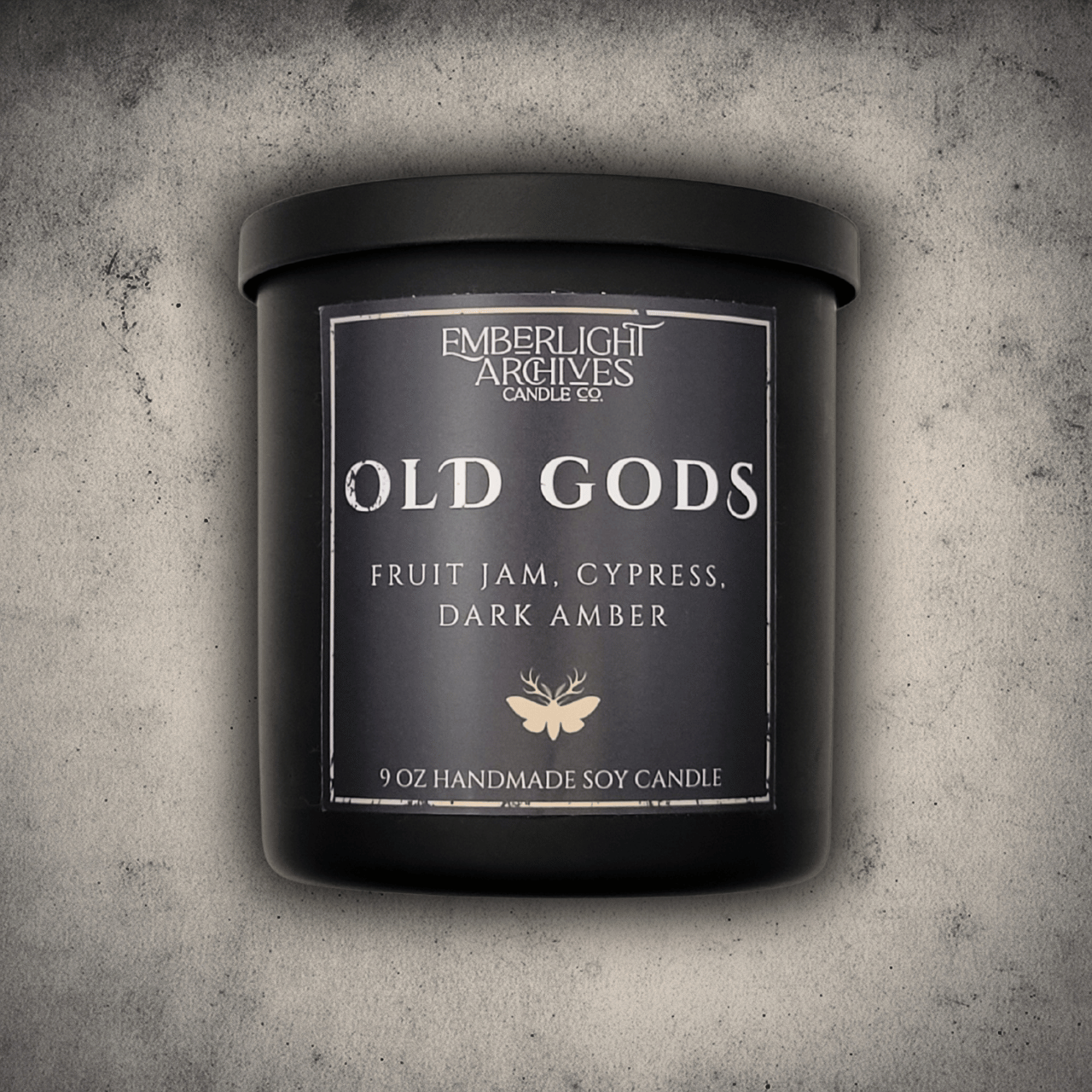 Emberlight Archives Old Gods candle in an 8oz black tin with dark label against a gray stone background, Fruit Jam & Musk scent.