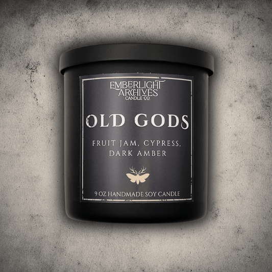 Emberlight Archives Old Gods candle in an 8oz black tin with dark label against a gray stone background, Fruit Jam & Musk scent.